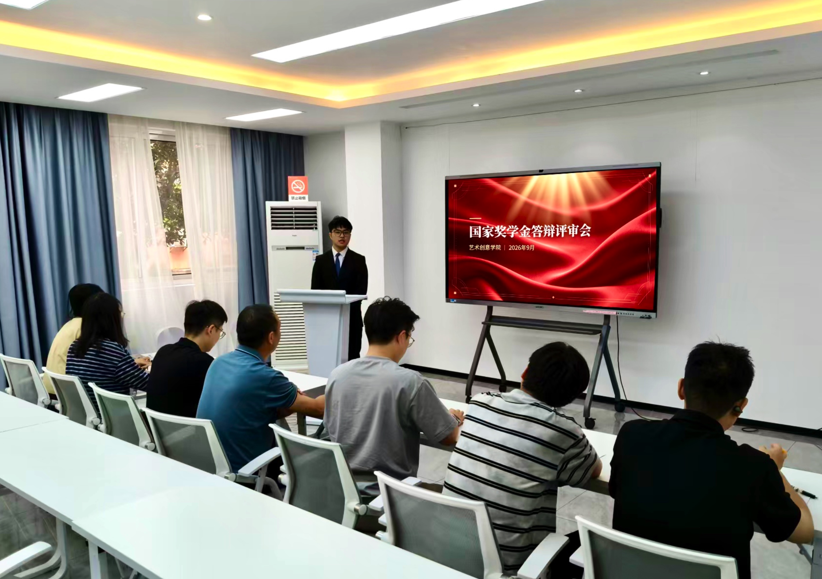 【图片1】答辩会现场全景:候选人在台汇报,投影显示“国家奖学金答辩评审会”
