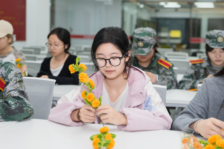 【图片1】志愿者们围坐桌前,制作黄色手工作品