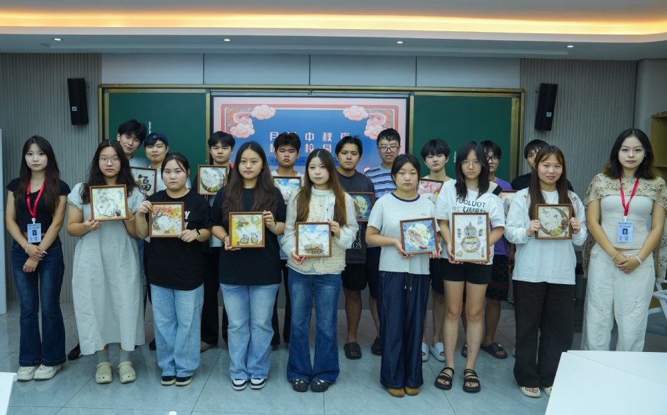 【图1】中秋系列主题活动师生合影(手持香氛画作品,背景为“月满校园 情暖中秋”主题板)