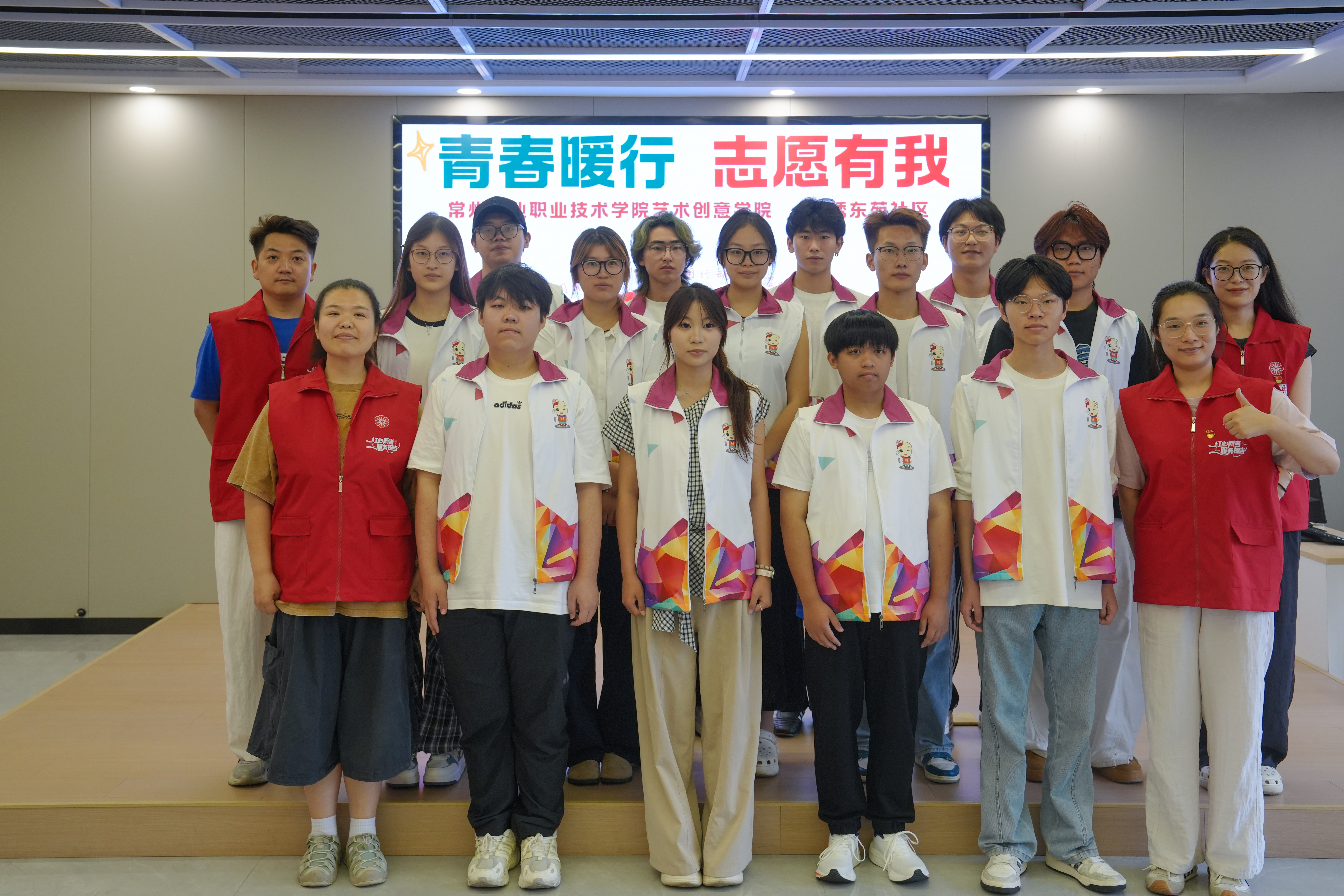 【图片1】“艺创同心”志愿者团队在“青春暖行 志愿有我”背景板前合影